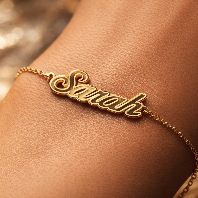 Gold bracelet with 'Sarah' on a wrist against a blurred background