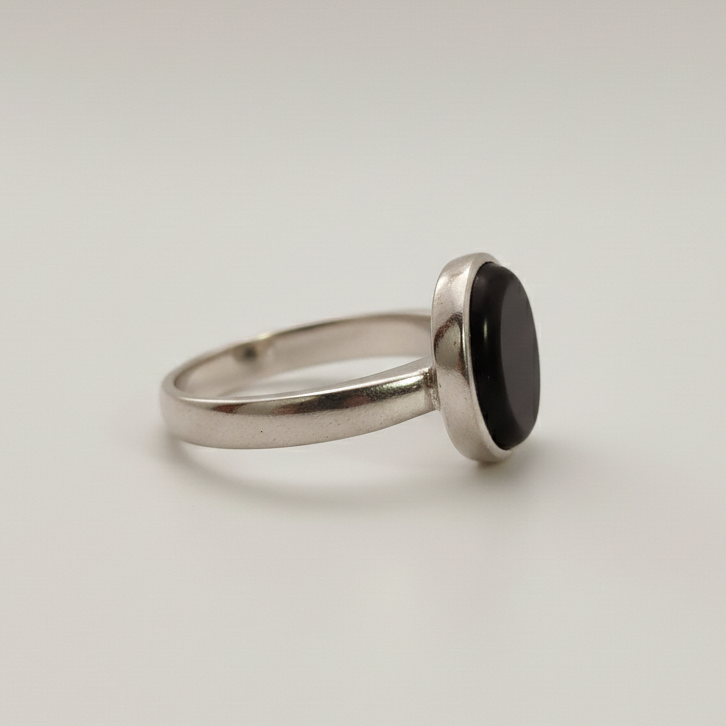 Silver ring with a black stone on a light gray background