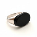 Silver ring with a black stone on a light gray background