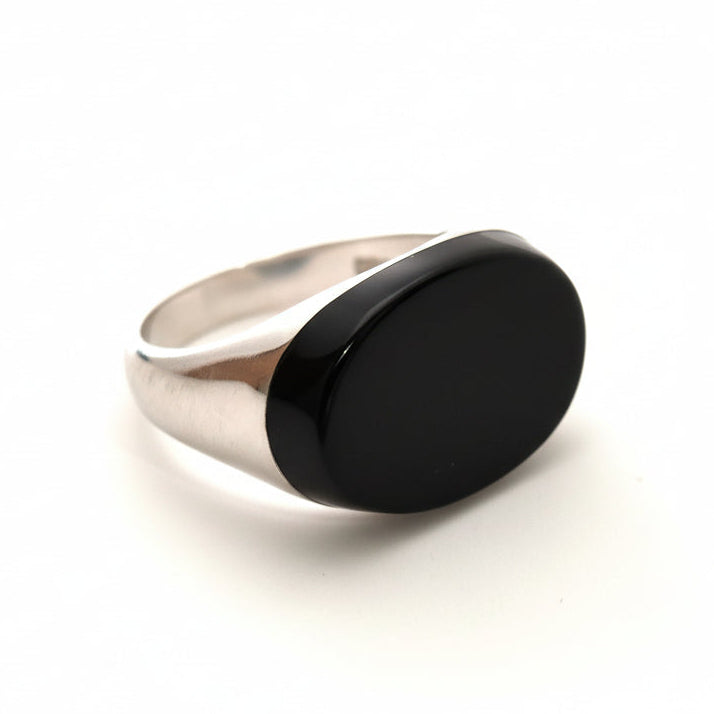 Silver ring with a black stone on a light gray background