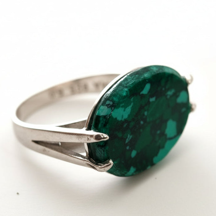 Silver ring with a large green gemstone on a white background