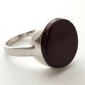 Silver ring with a dark brown stone on a light gray background