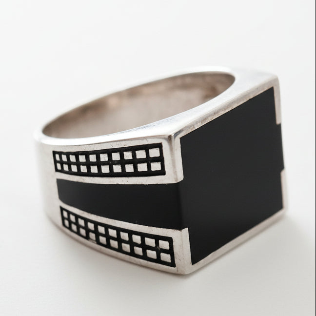Silver ring with black band on a light gray background