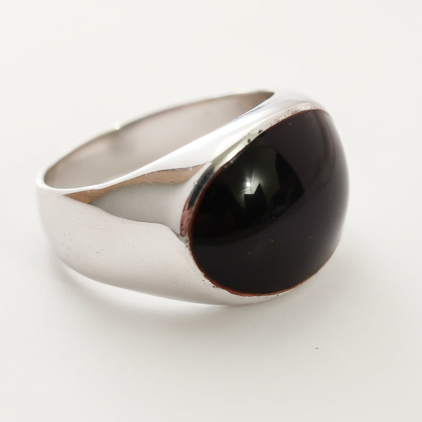 Silver ring with a black stone on a light gray background