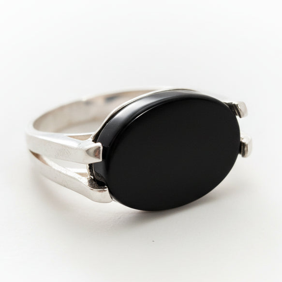 Silver ring with a black stone on a light gray background