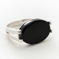 Silver ring with a black stone on a light gray background