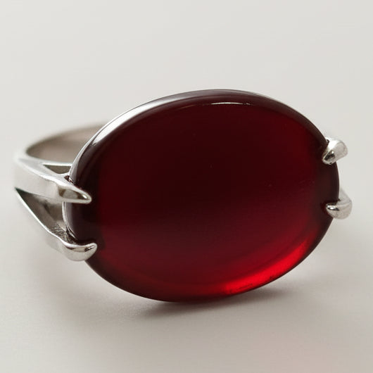 Silver ring with a red stone on a white background