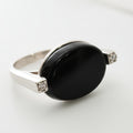 Silver ring with a black stone on a light gray background