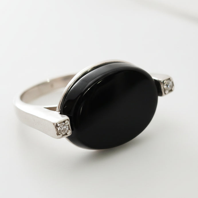 Silver ring with a black stone on a light gray background