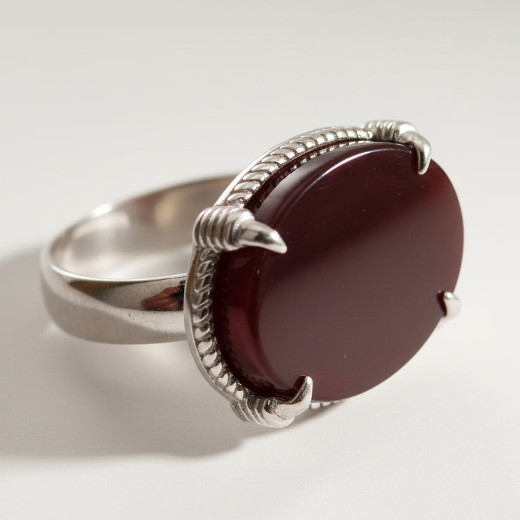 Silver ring with a dark brown stone on a light background