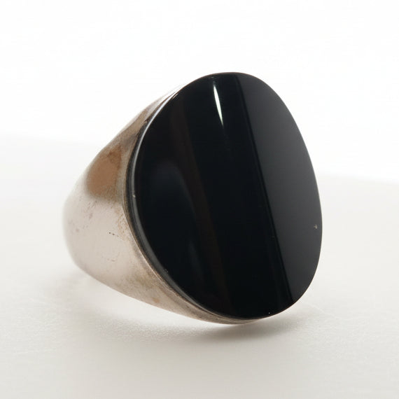 Silver ring with a black stone on a light gray background