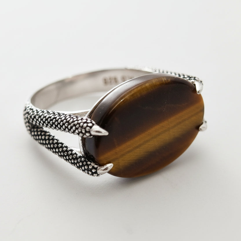 Silver ring with a brown stone on a light gray background