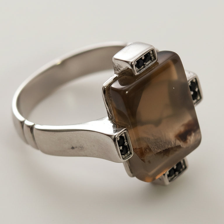 Silver ring with a brown gemstone on a light gray background