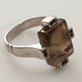 Silver ring with a brown gemstone on a light gray background