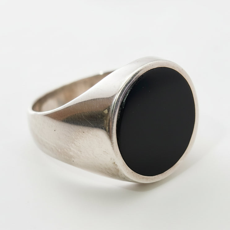 Silver ring with a black stone on a light gray background