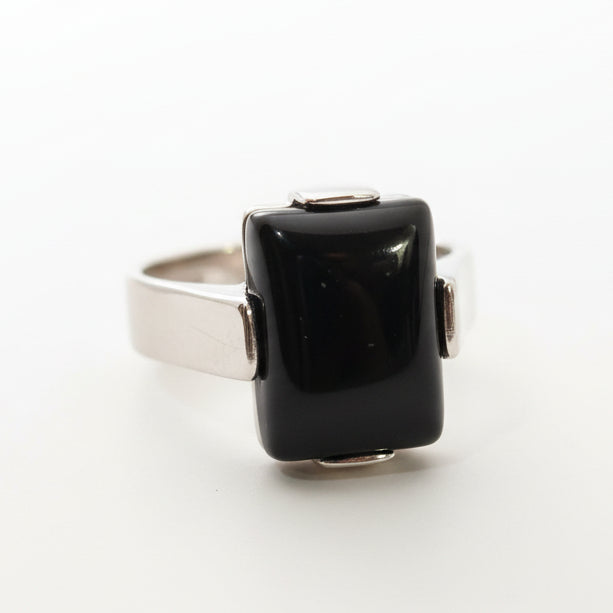 Silver ring with a black gemstone on a light gray background