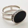 Silver ring with black stone on a light gray background