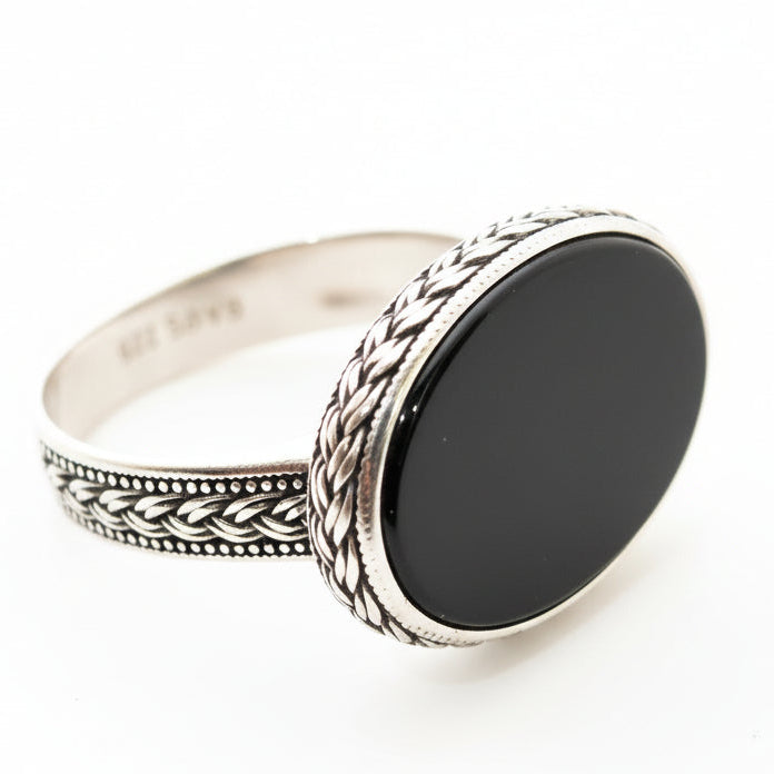 Silver ring with black stone on a light gray background