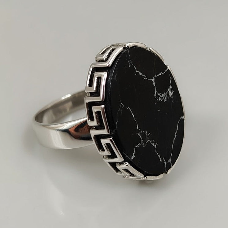 Silver ring with a black stone on a light gray background