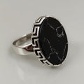 Silver ring with a black stone on a light gray background