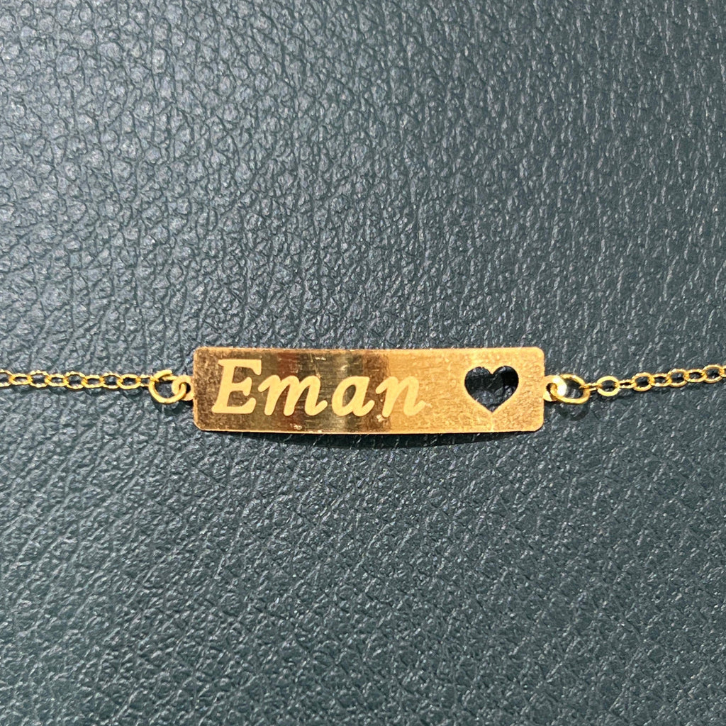 Gold bracelet with 'Eman' engraved on a textured gray background