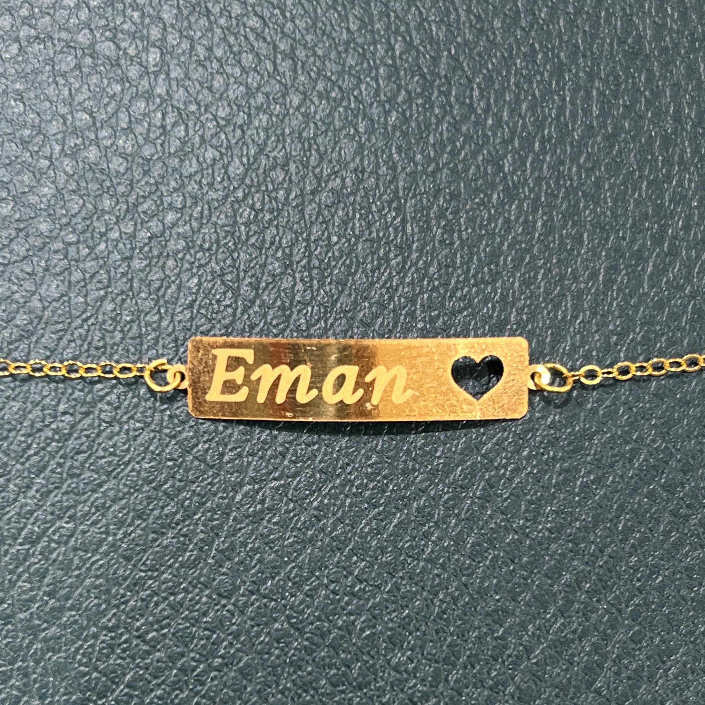 Gold bracelet with 'Eman' engraved on a textured gray background